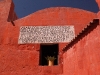 The simple shapes of the stonework and the brick red paint dazzle in the sun beneath the deep azure sky